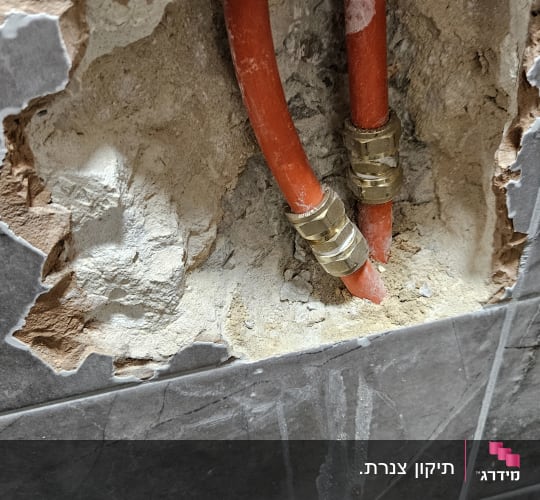 צינורות אדומים עם מחברים בקיר שבור